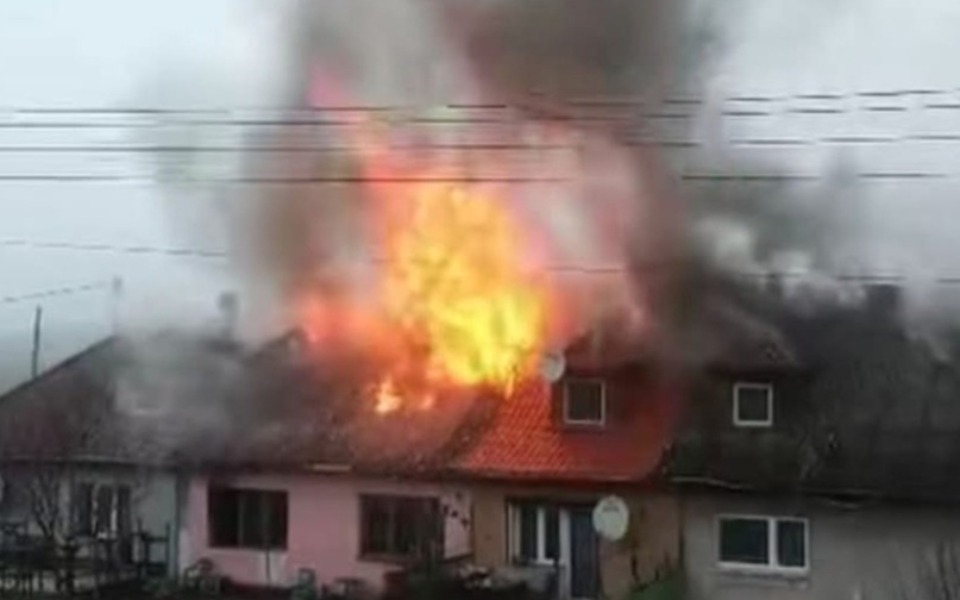 
        Dom w płomieniach, z dymem unoszącym się w powietrzu.
    