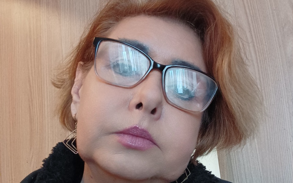 
        Portret kobiety z okularami, z wyraźnym wyrazem twarzy.
    