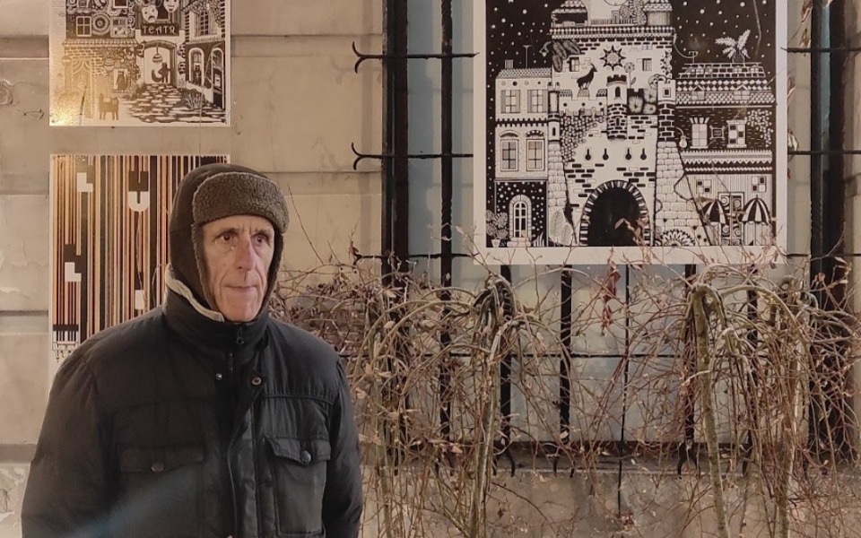 
        Mężczyzna w ciepłej czapce stoi przed muralem na ścianie.
    