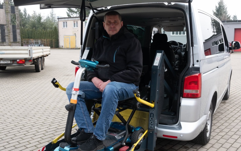 
        Mężczyzna siedzący na wózku inwalidzkim w samochodzie.
    