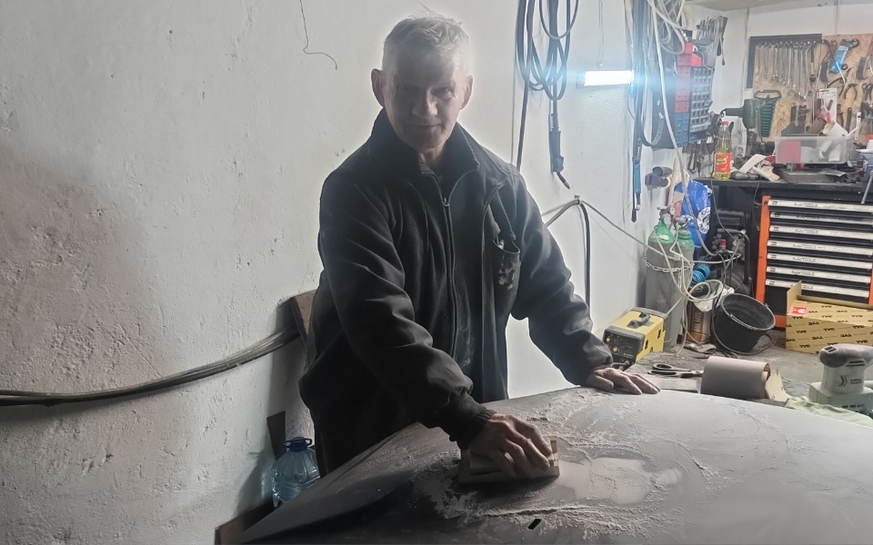 
        Mężczyzna pracujący w warsztacie, szlifujący powierzchnię.
    