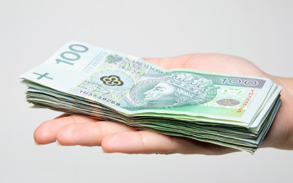 
        Ręka trzymająca stos banknotów 100 zł.
    
