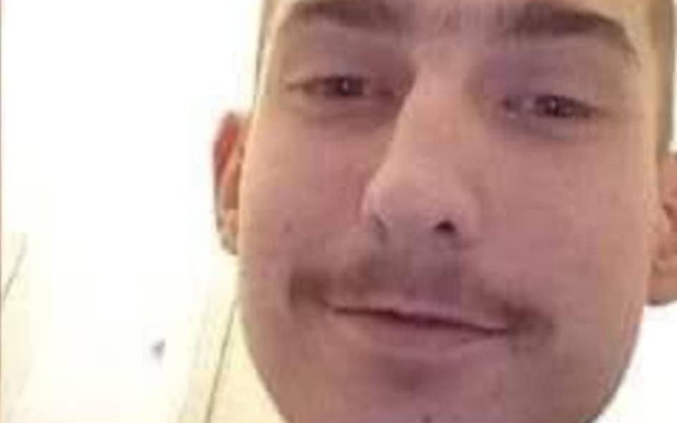 
        Mężczyzna z wąsami, uśmiechający się do kamery.
    