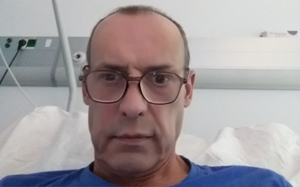 
        Mężczyzna w okularach leży w szpitalnym łóżku.
    