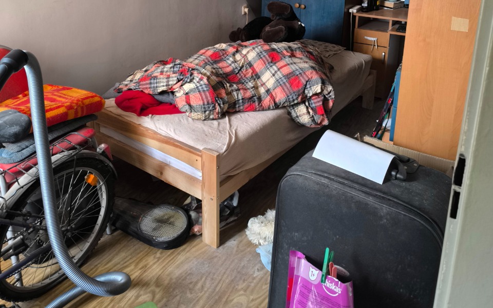 Zabałaganiony pokój z łóżkiem i walizką.