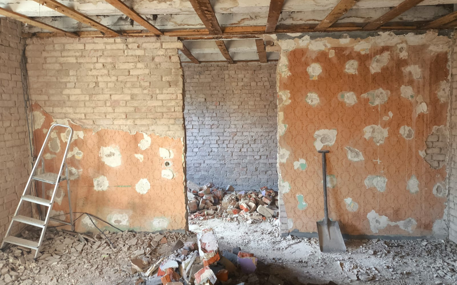 
        Pusty pokój w trakcie remontu, z odsłoniętymi ścianami.
    