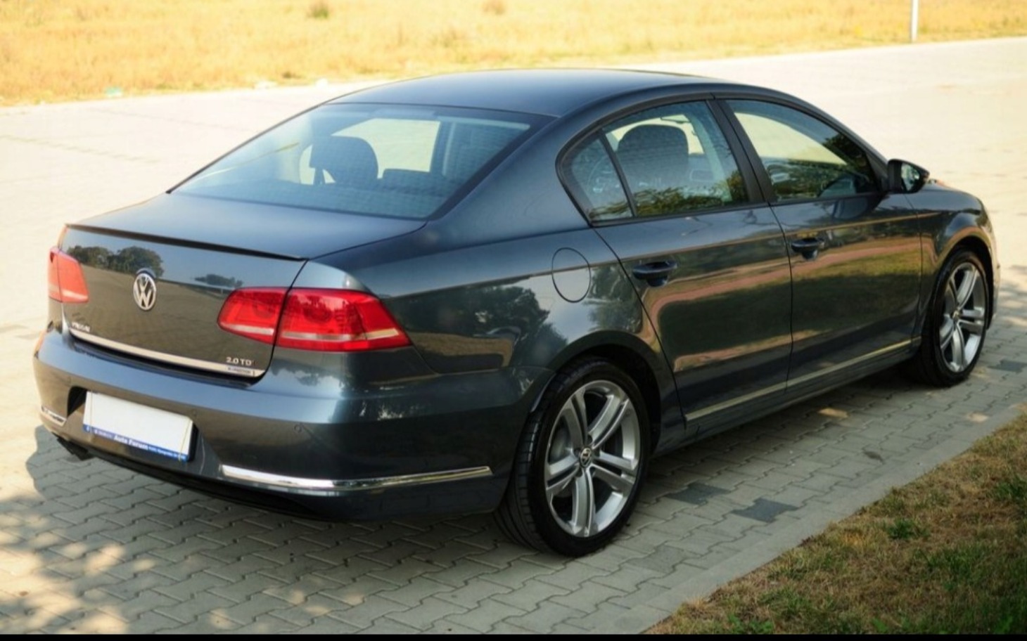 
        Czarny samochód osobowy zaparkowany na drodze w słoneczny dzień.
    