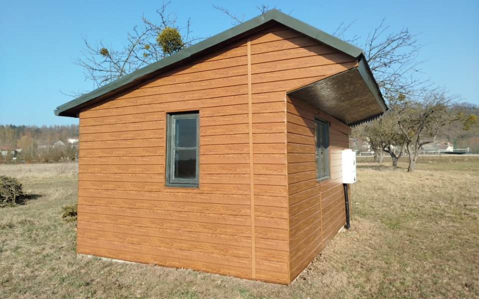 
        Nowoczesny domek z drewnianym wykończeniem na działce.
    