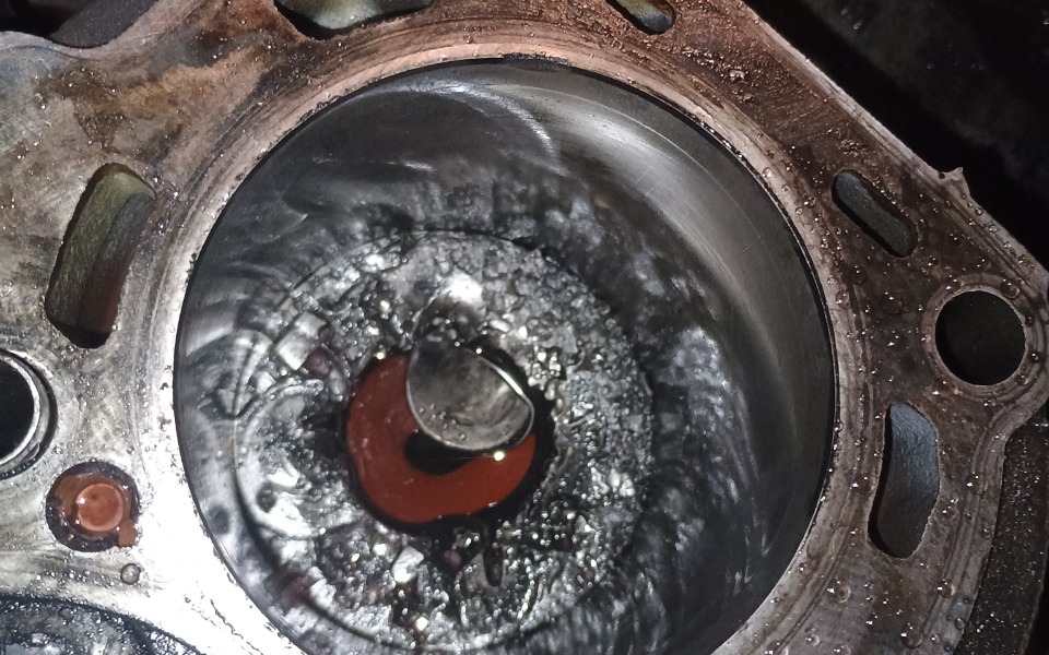 
        Widok na uszkodzoną część silnika, z widocznymi zanieczyszczeniami.
    