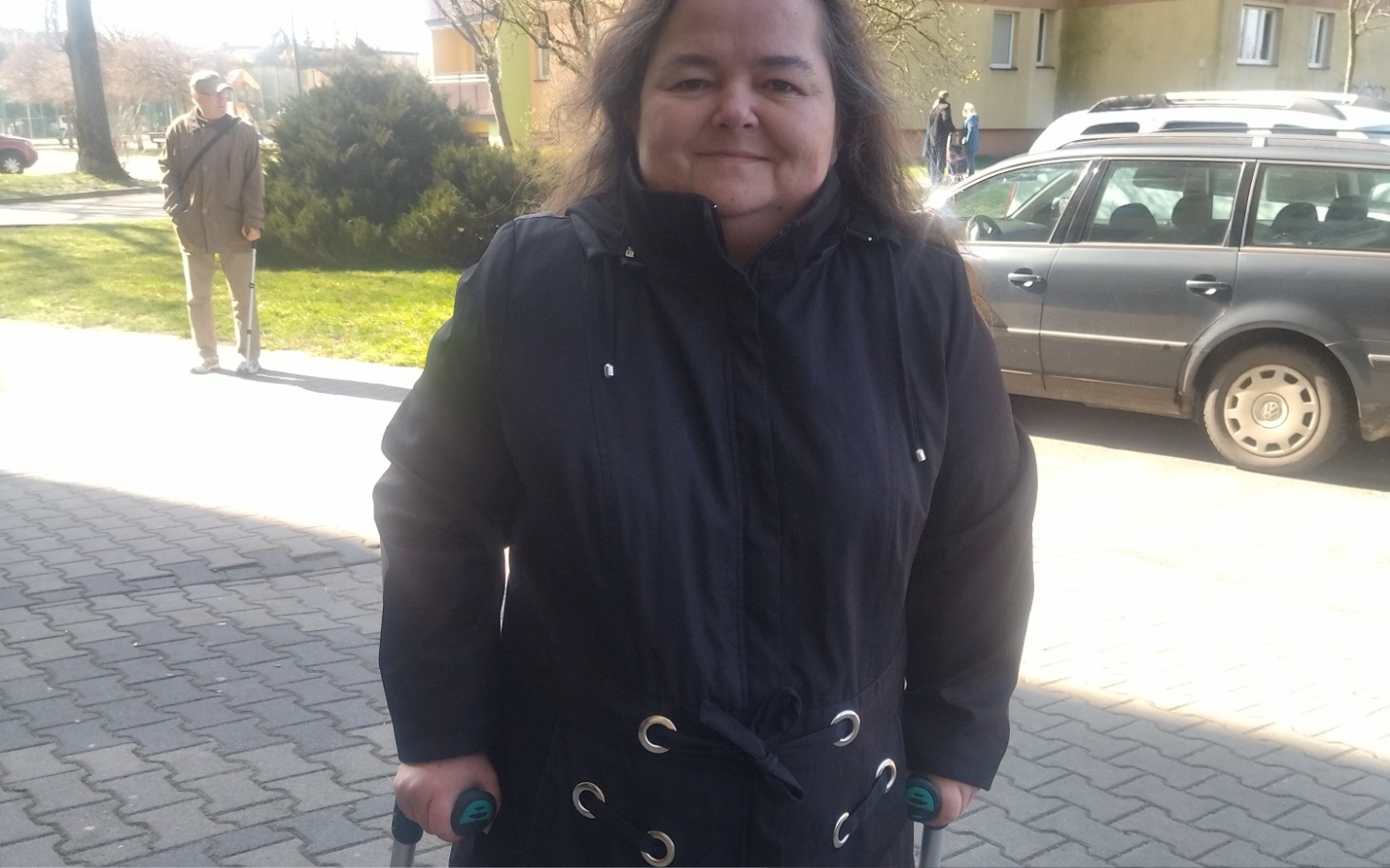 
        Kobieta z wózkiem spacerowym na chodniku.
    