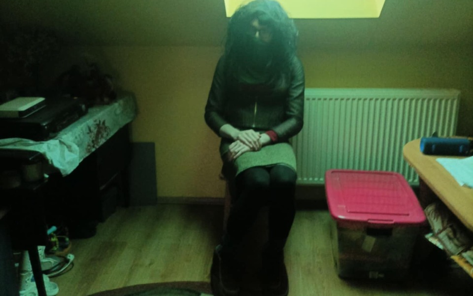 
        Osoba siedząca w ciemnym pomieszczeniu z dziwnym oświetleniem.
    