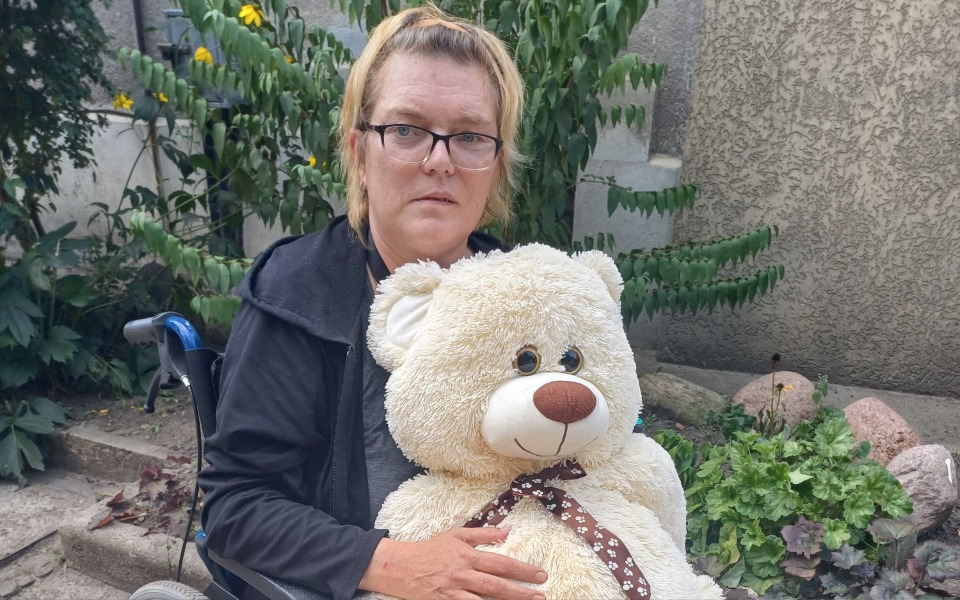 Kobieta w wózku inwalidzkim trzymająca pluszowego misia.