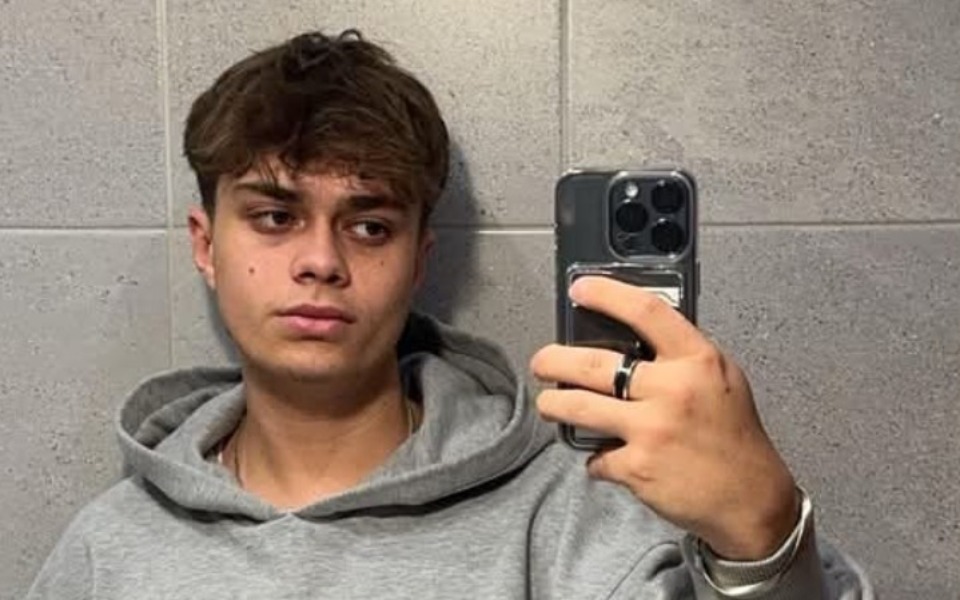 
        Młody mężczyzna w szarej bluzie, robiący selfie w lustrze.
    