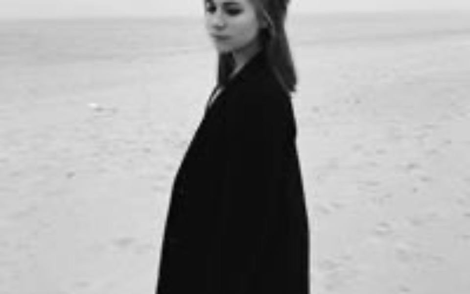 
        Kobieta w czarnym płaszczu spaceruje po plaży.
    