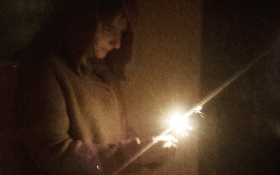 
        Osoba trzymająca iskrzącą się petardę w ciemnym pomieszczeniu.
    