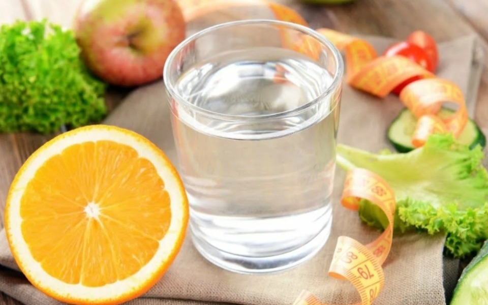 
        Szklanka wody obok owoców i warzyw na stole.
    