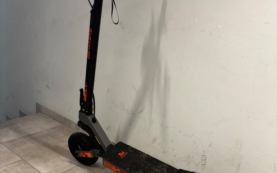 
        Skuter elektryczny stojący na podłodze w jasnym pomieszczeniu.
    