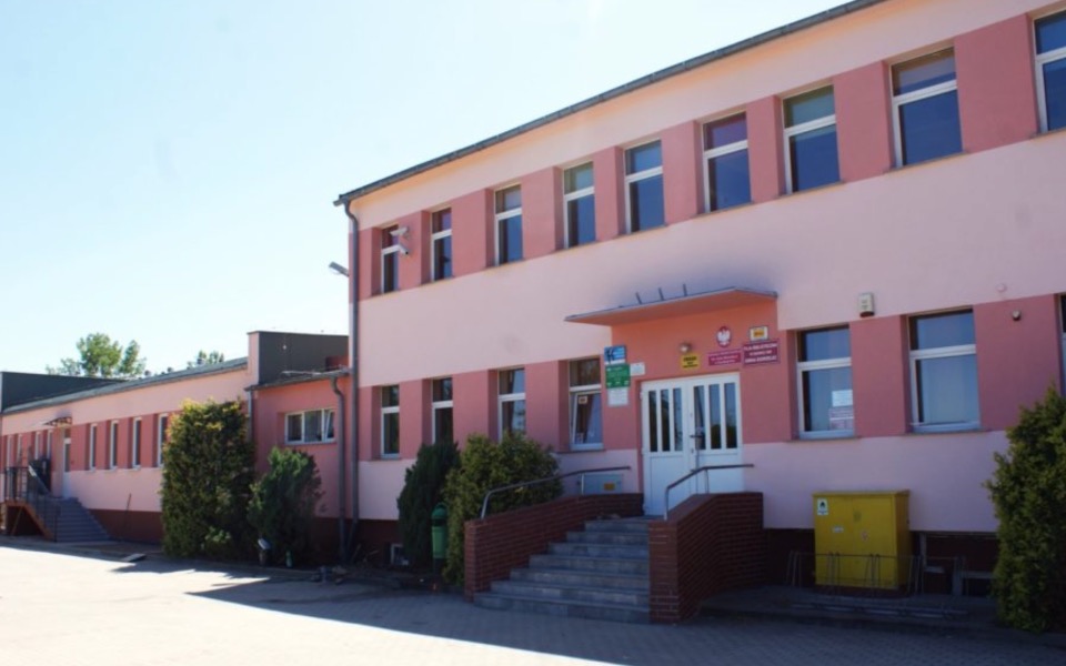 
        Widok na budynek szkoły z różowymi ścianami.
    