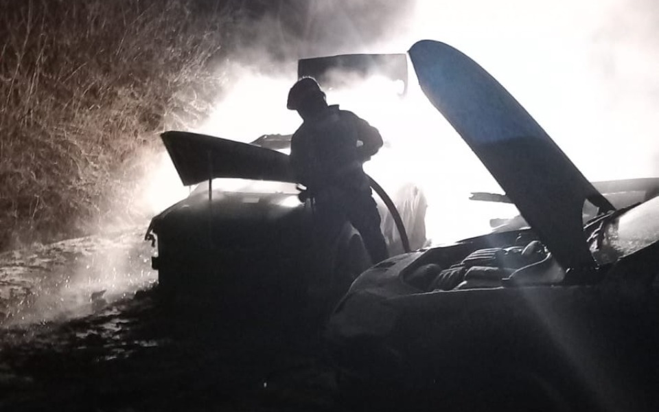 
        Strażak gaszący pożar w ciemnej scenerii z dymem.
    