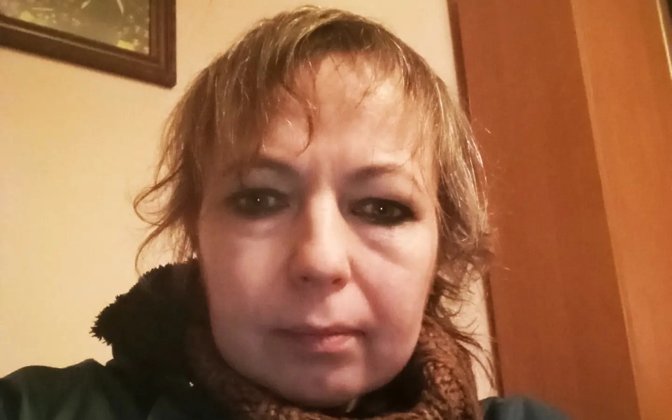 
        Portret kobiety z krótkimi włosami, w domowym otoczeniu.
    