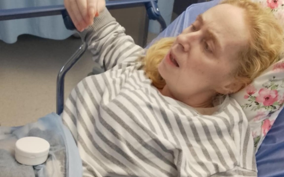 
        Kobieta w szpitalnym łóżku, wyraźnie zmęczona.
    