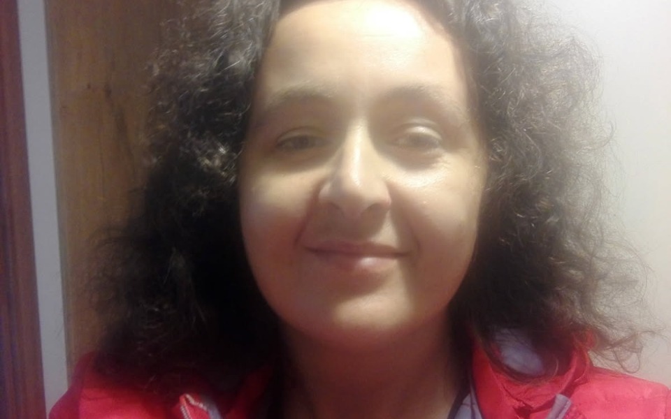 
        Kobieta z kręconymi włosami, uśmiechająca się do kamery.
    