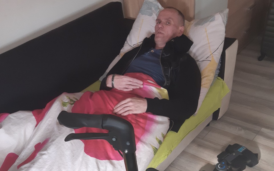 
        Mężczyzna leżący na kanapie, przykryty kocem.
    