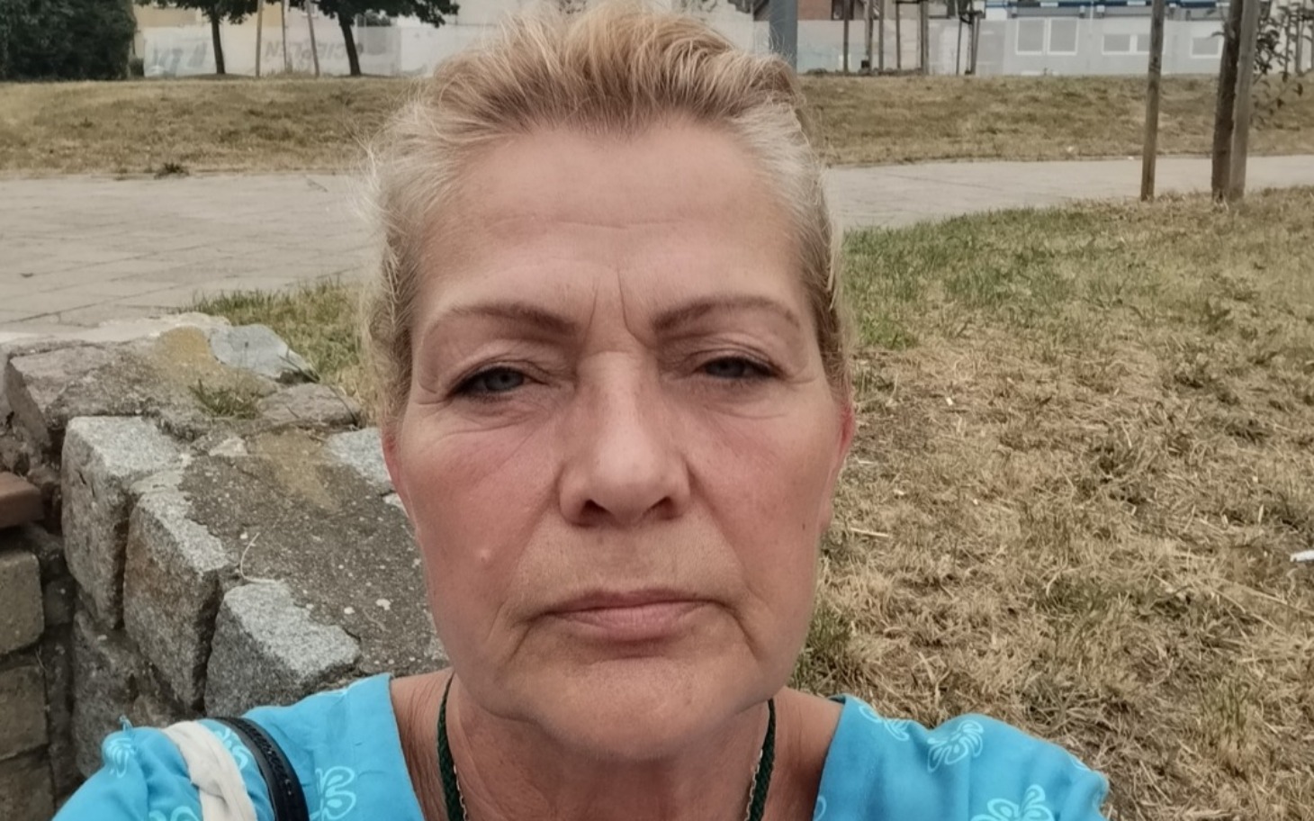 
        Portret kobiety w plenerze, z poważnym wyrazem twarzy.
    