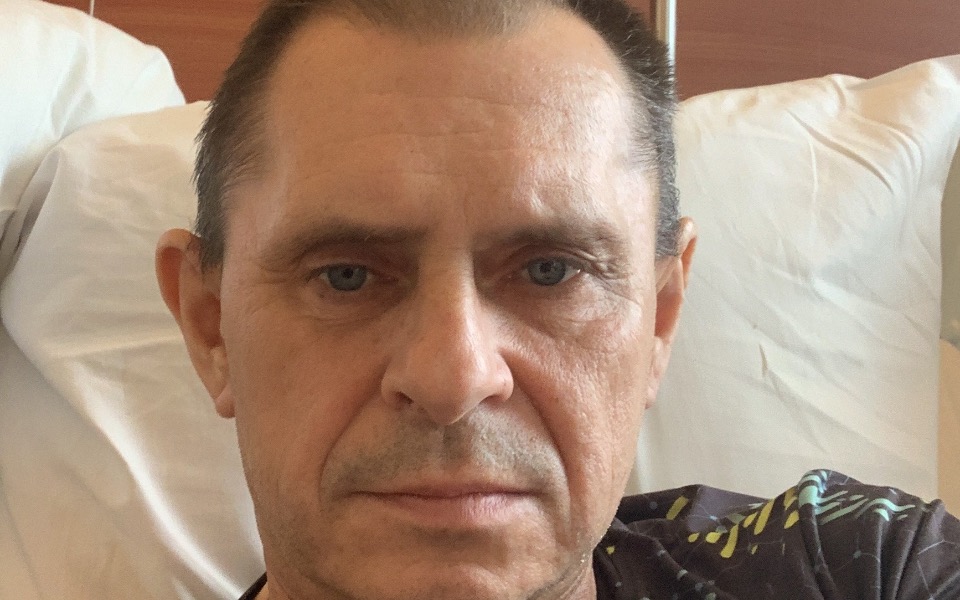 
        Mężczyzna w szpitalnym łóżku, z poważnym wyrazem twarzy.
    