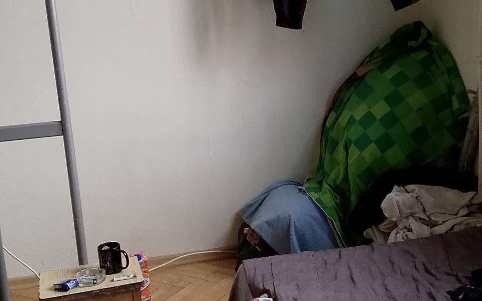 
        Pusty pokój z pościelą i ubraniami na podłodze.
    