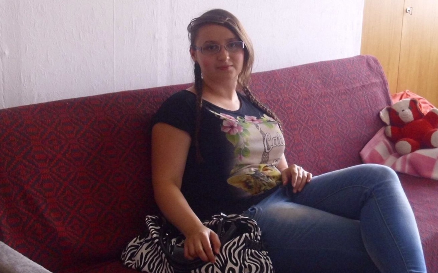 
        Młoda kobieta siedzi na kanapie, uśmiechnięta.
    