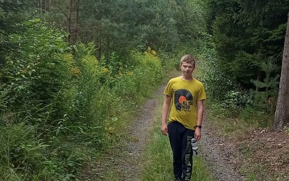 
        Młody chłopak spacerujący po leśnej ścieżce.
    