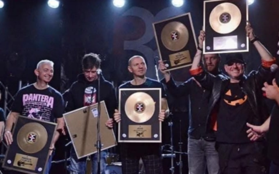 
        Zespół muzyczny z nagrodami na scenie.
    