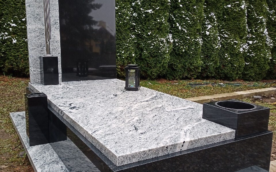 
        Pomnik z lampionem i czarnym pojemnikiem.
    