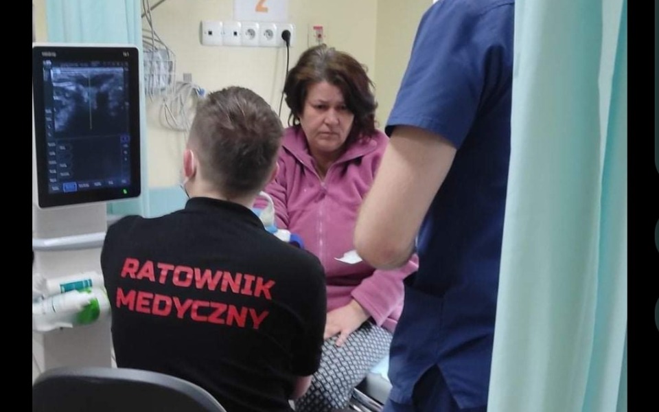 
        Ratownik medyczny udzielający pomocy pacjentce.
    