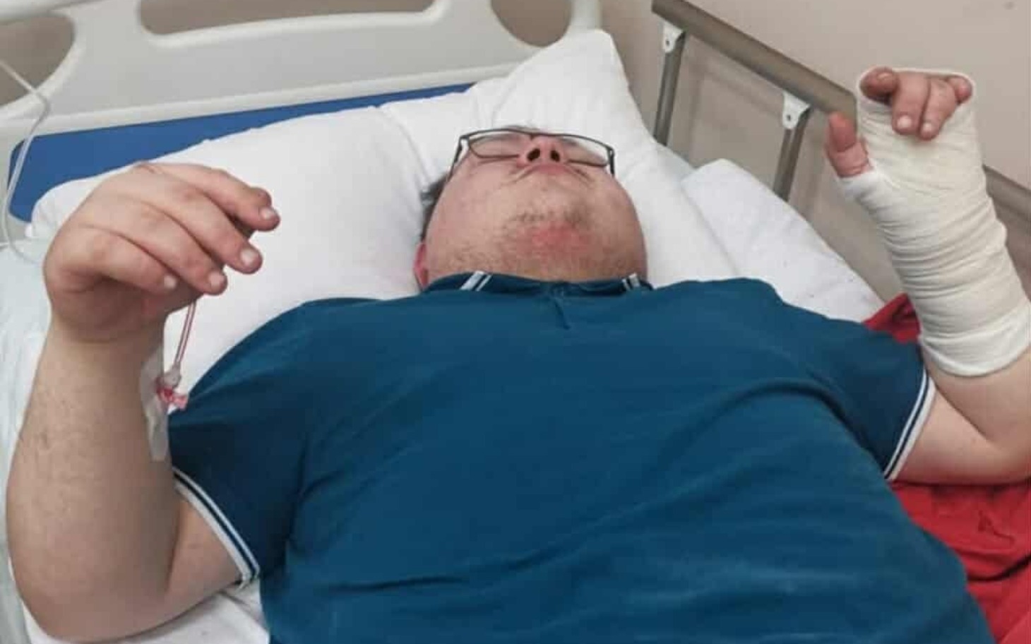 
        Mężczyzna leżący na łóżku szpitalnym z opatrunkiem na ręce.
    