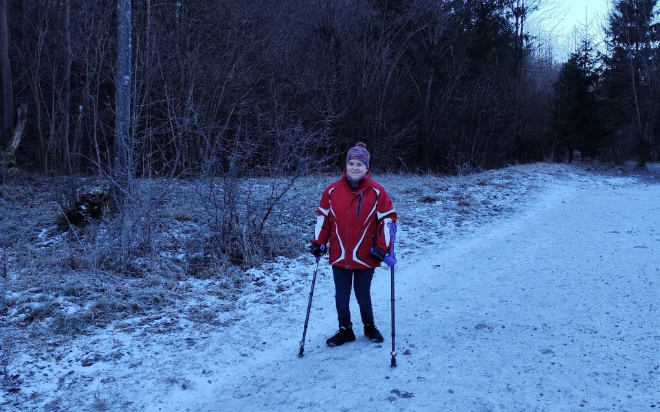 
        Osoba spacerująca w zimowym lesie, ubrana w czerwoną kurtkę.
    