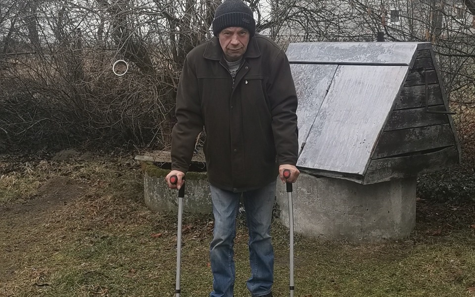 
        Mężczyzna z balkonikiem, w otoczeniu przyrody.
    