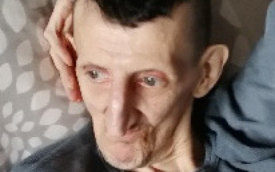 
        Mężczyzna z wyrazem twarzy, siedzący na kanapie, z ręką na głowie.
    