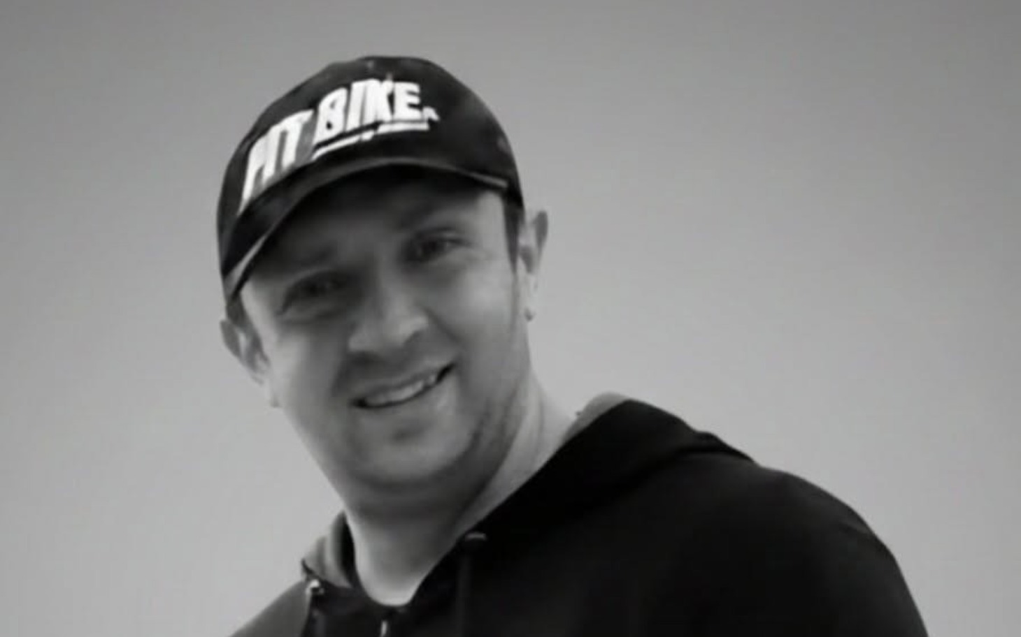 
        Mężczyzna w czapce uśmiechający się do kamery.
    