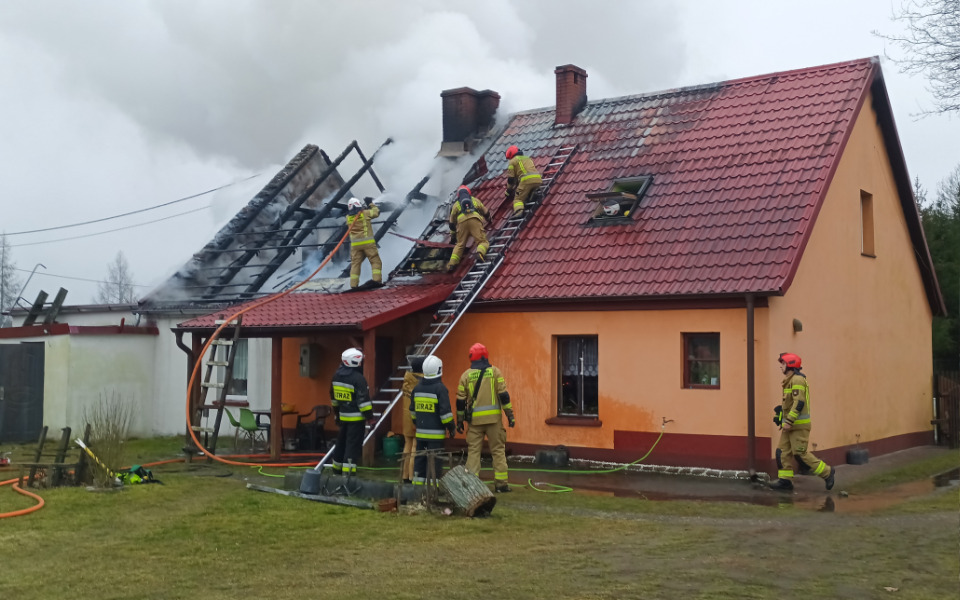 
        Strażacy gaszący pożar na dachu domu.
    