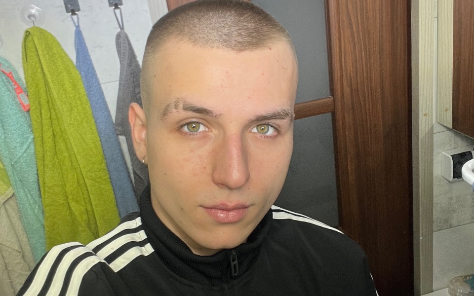 
        Młody mężczyzna z krótkimi włosami, patrzący w lustro.
    