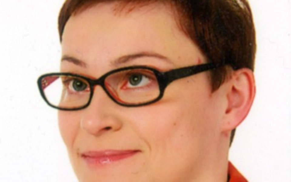 
        Portret kobiety w okularach z uśmiechem.
    