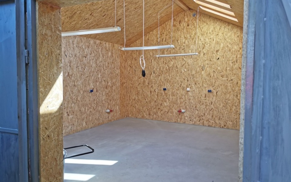 
        Pusty pokój z drewnianymi ścianami i betonową podłogą.
    