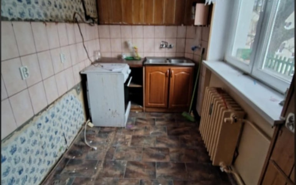 
        Zniszczona kuchnia z brudnymi ścianami i podłogą.
    