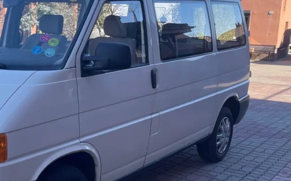 
        Biały van zaparkowany na podjeździe, z widocznymi naklejkami.
    