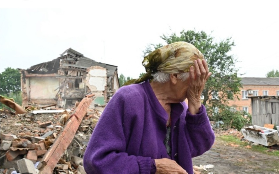 
        Smutna starsza kobieta w zniszczonym otoczeniu po katastrofie.
    