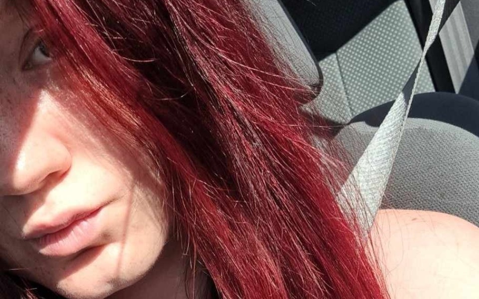 
        Młoda osoba z długimi, czerwonymi włosami w samochodzie.
    