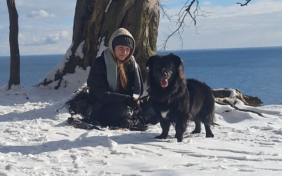 
        Kobieta z psem na tle zimowego krajobrazu.
    