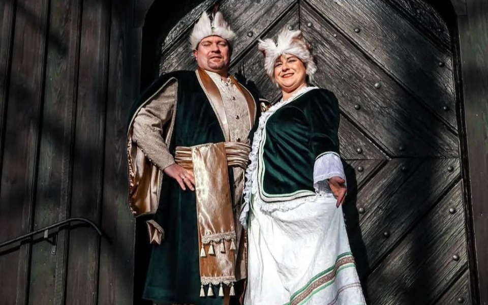 
        Para w tradycyjnych strojach, pozująca przed drewnianą bramą.
    